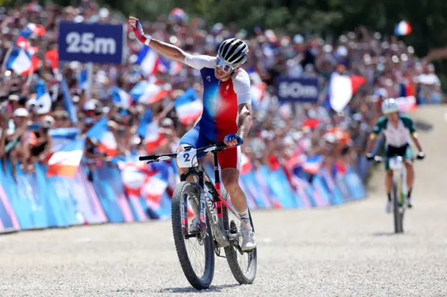 Victor Koretzky raising his hand to the crowd as he crosses the finish line