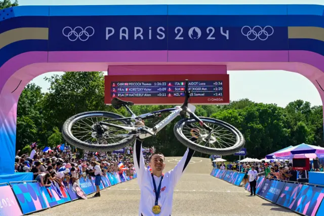 Tom Pidcock celebrates with bike and gold medal