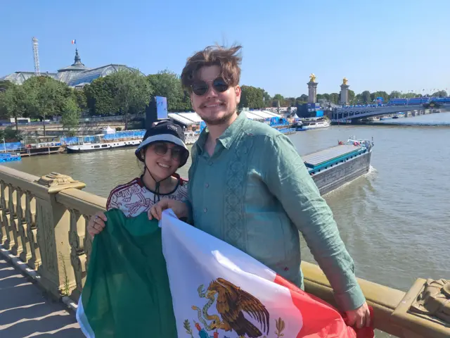 A couple hold a Mexican on a bridge next to the River Seine