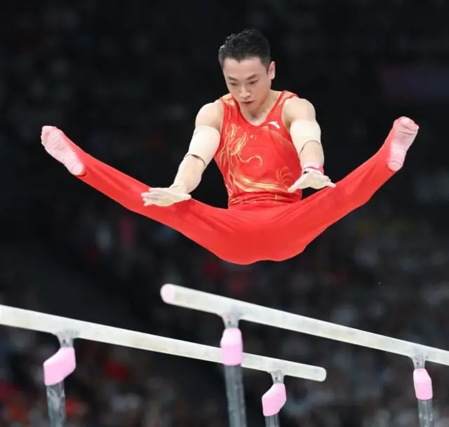 Jingyuan Zou performs on parallel bars