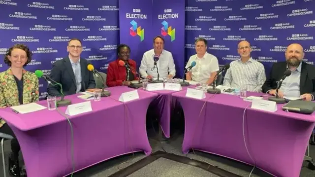 Six political candidates and the BBC's Chris Mann sat at a purple table