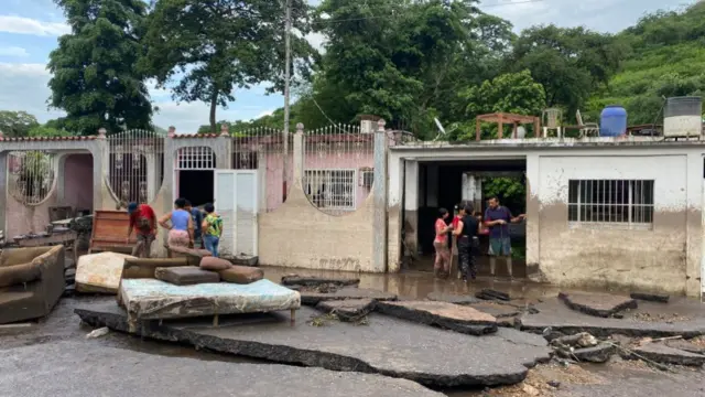 Residents try to recover their belongings from their homes after they were flooded with water from a swollen river