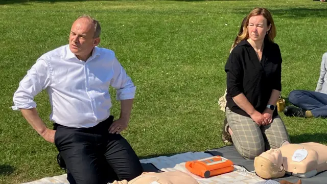 Sir Ed Davey and Chelmsford Liberal Democrat candidate Marie Goldman kneeling in a park about to perform cpr on a mannequin