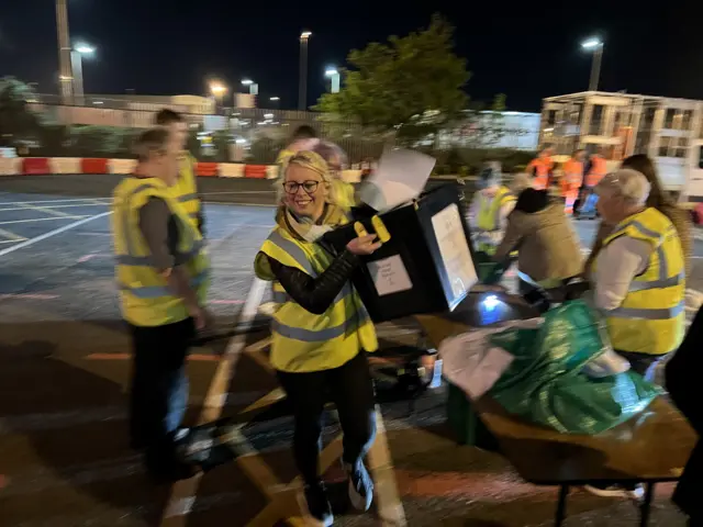 A woman carrying in a ballot box to a general election count