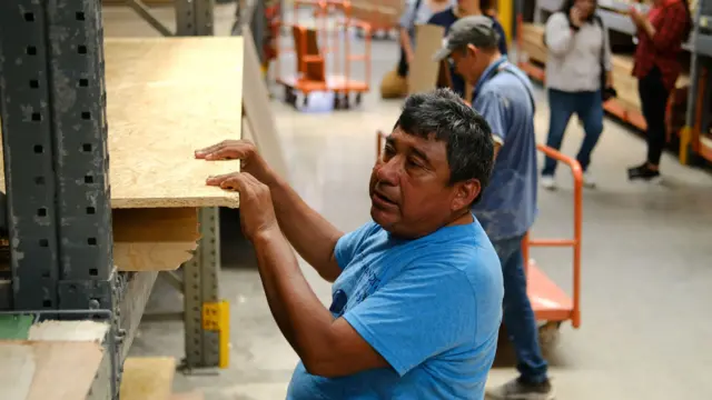 Man grabs ply wood from a shelf