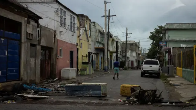 A man walks in the downtown street market area, with debris strewn across the floor.