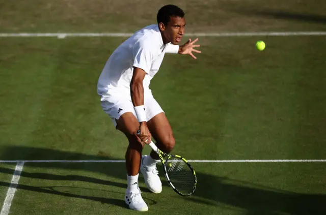 Auger-Aliassime watches the ball to complete a backhand