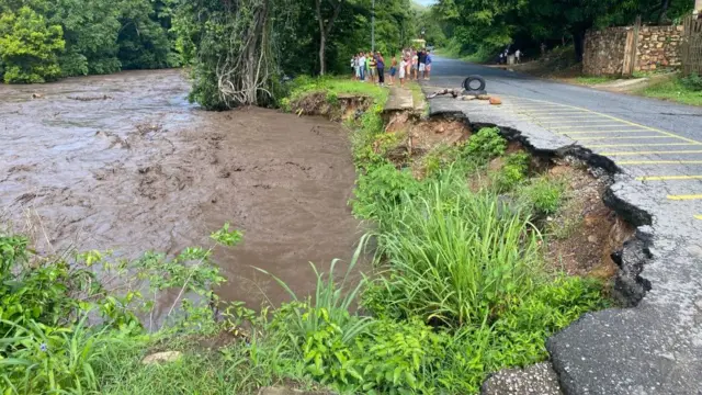 People watch a river swell due to heavy rains following the passage of Hurricane Beryl on the road from Cumana to Cumanacoa, Sucre State, Venezuela, on July 2, 2024.