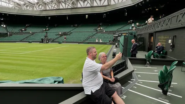 Man and Woman sitting down taking a picture in Centre Court