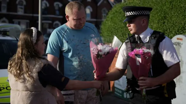 Police are handed flowers by people paying tribute