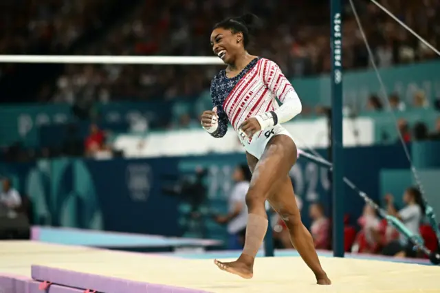 Biles smiles gleefully after performing her uneven bars routine