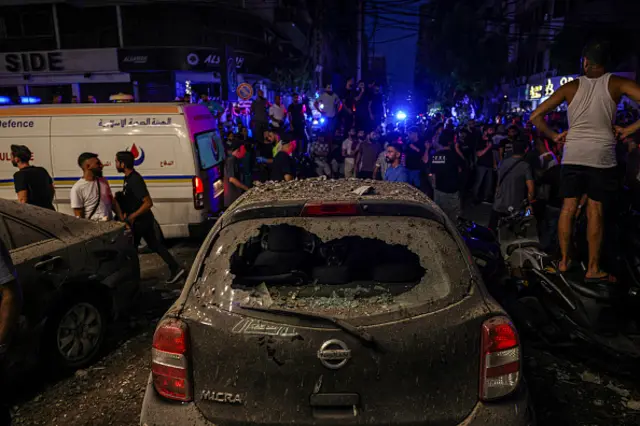 Bystanders gather near the site of an Israeli military strike in a Beirut's southern suburb