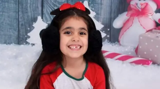 Alice, wearing ear muffs, is pictured in front of a wintery backdrop