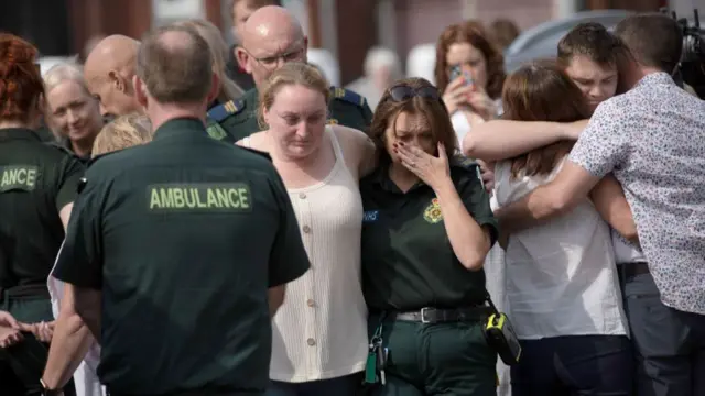 Emergency personnel comfort members of the public near the scene of yesterday's attack