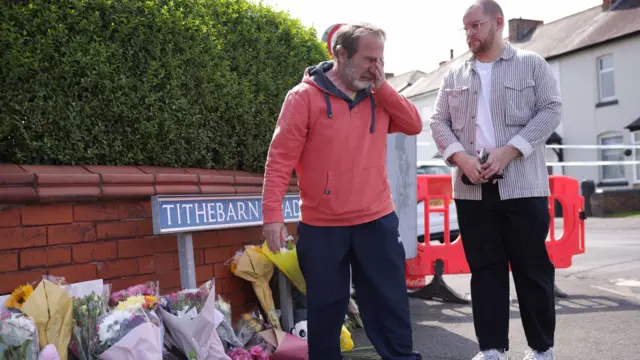 Two men next to flowers near the scene in Southport