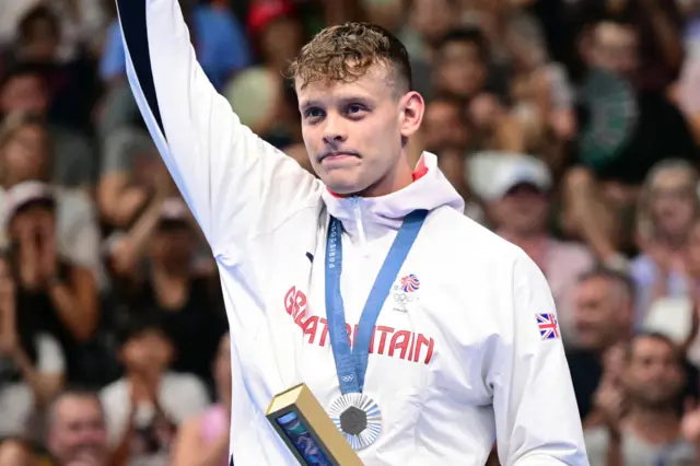 Matt Richards holds up his arms and wears an Olympic silver medallist around his neck