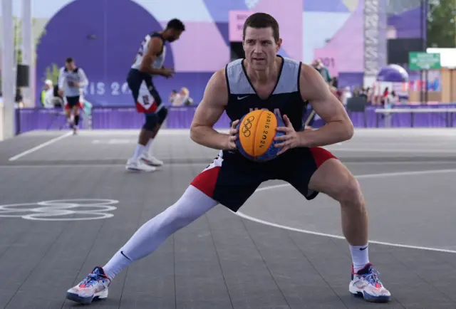 Jimmer Fredette holds a basketball and stretches