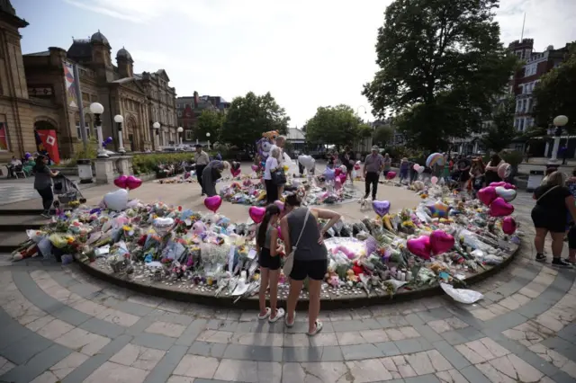 People look at bouquets of flowers in the courtyard outside the centre, there are also many balloons shaped like hearts