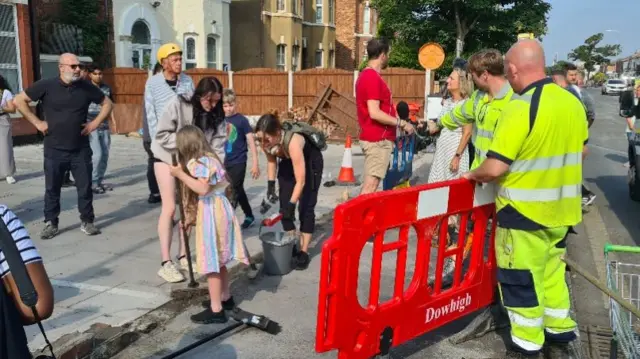 Adults and children cleaning streets