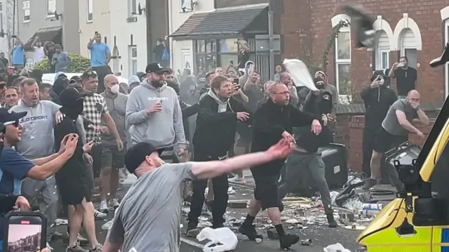 Rioters attacking police at around 21:00 BST on Tuesday