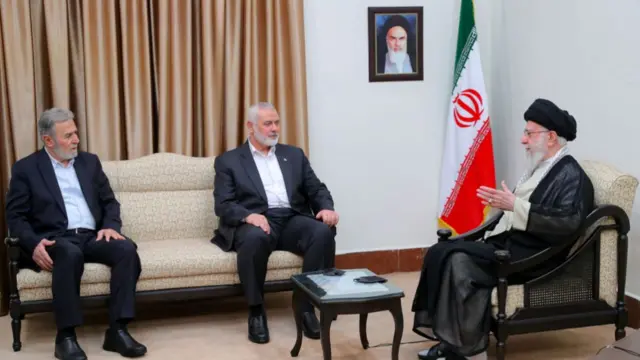 Iranian Supreme Leader Ayatollah Ali Khamenei meeting with  Secretary General of the Palestinian Islamic Jihad Movement Ziyad al-Nakhalah (L) and the head of the Palestinian Hamas group's political bureau Ismail Haniyeh. All three are sat down.