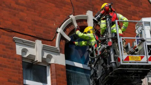 Close up shot of two firefighters replacing a cracked window