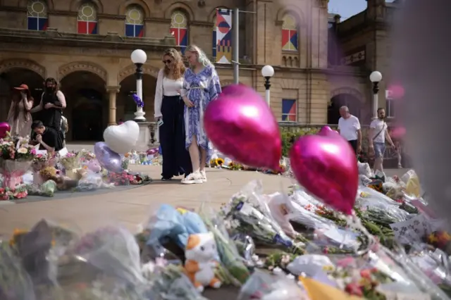 Two women look at tributes