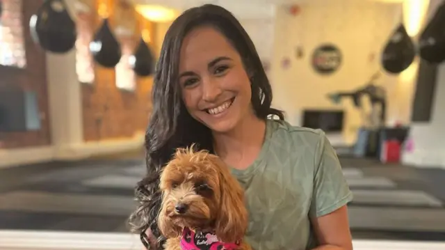 Leanne Lucas holding a dog and smiling