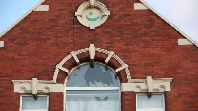 An arch window in a brick building is shattered