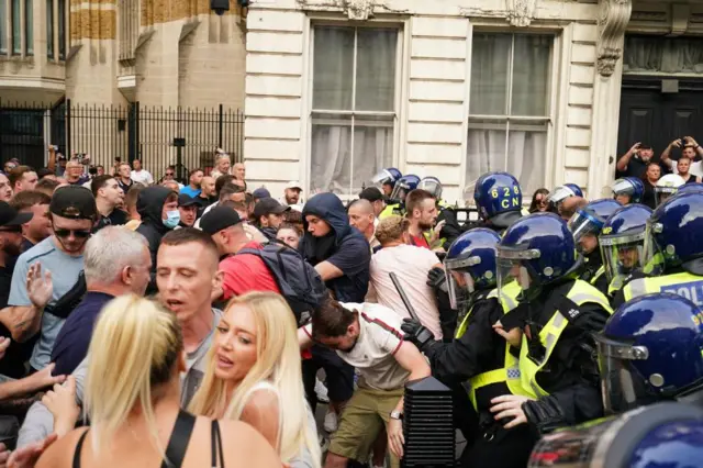 A crowd of protesters pressing up against a line of police in riot gear