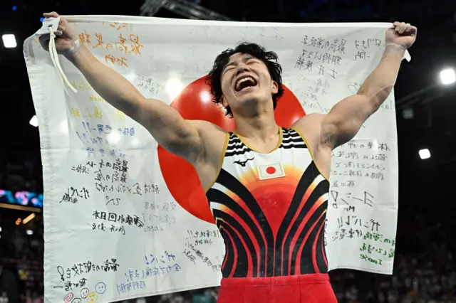 Oka celebrates his gold medal by holding aloft the Japan flag