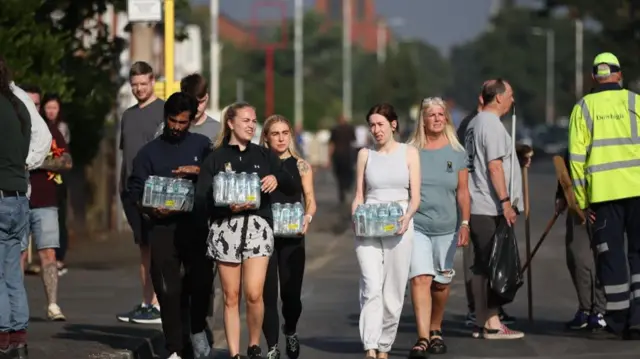 Residents carry water for the volunteers