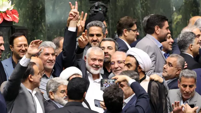 Hamas leader Ismail Haniyeh flashes victory sign as he is surrounded by Iranian lawmakers at the Iranian parliament in Tehran, Iran,