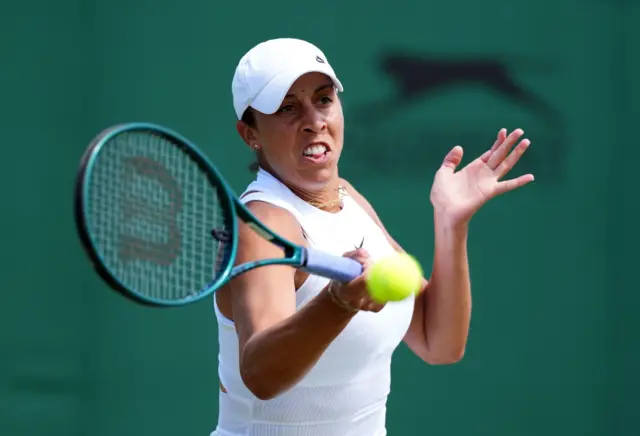 Madison Keys hits a forehand shot wearing a white dress and white cap