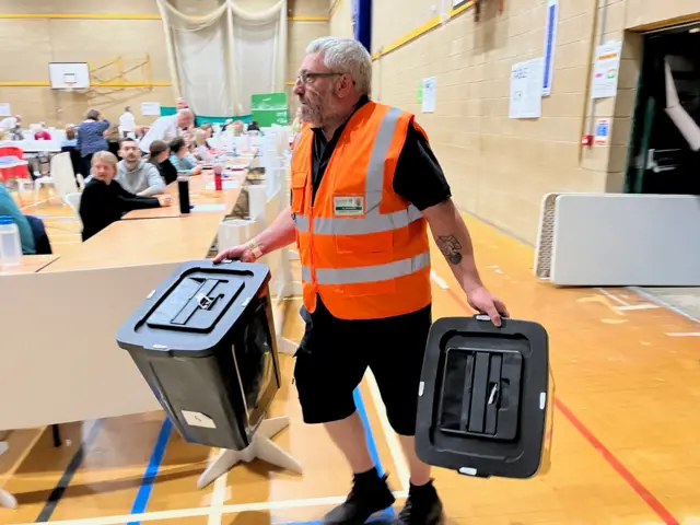 A council worker carries two ballot boxes into Clacton Leisure Centre