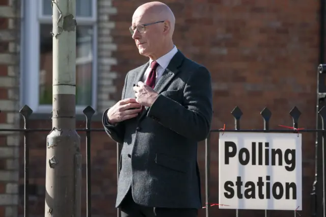 Swinney stands outside a polling station