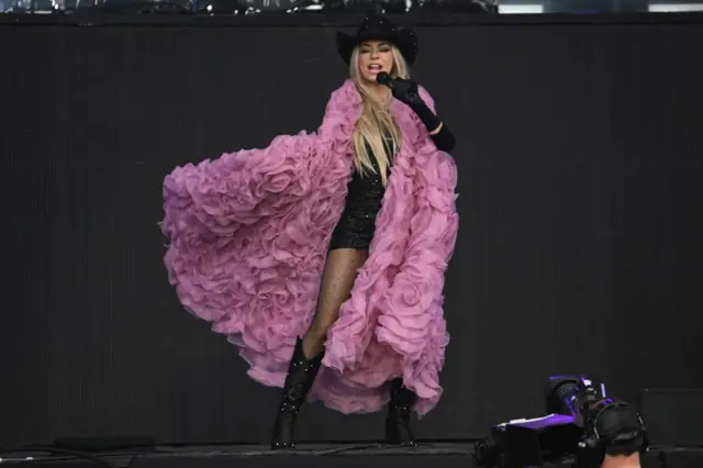 Singer Shania Twain on stage with a pink coat on.