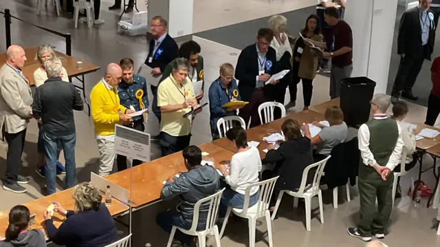 Party workers watching verification of ballots cast