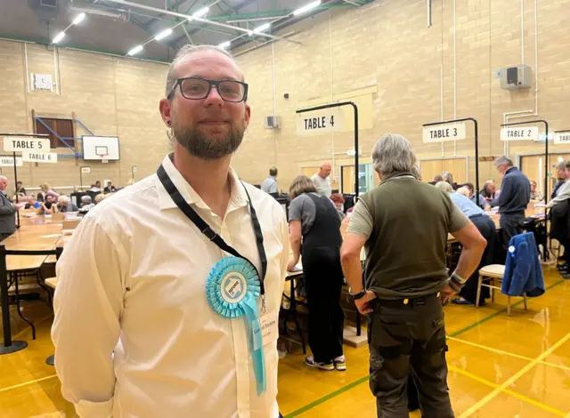 Man in white shirt, blue tie and glasses smiling