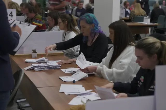 Three women at a table count votes