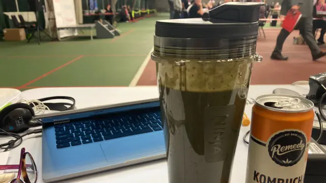 image shows a green smoothie and a can on kombucha