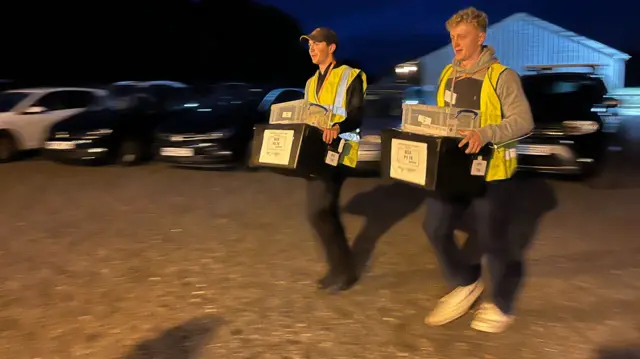 Volunteers carrying ballot boxes