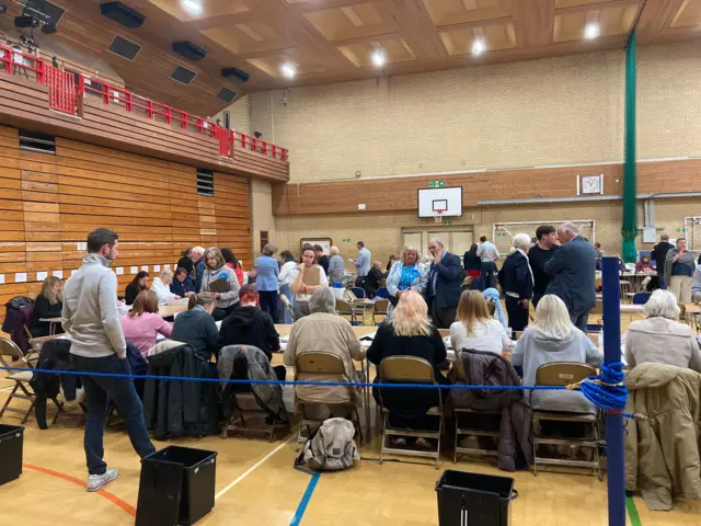 Boxes arriving at the Westmorland and Lonsdale county with rows of people sitting at desks ready to count them