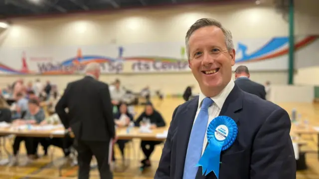 Andrew Johnson smiling at the camera with counting teams in the background