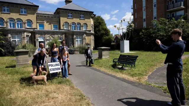 People take photos at a polling station in Brighton