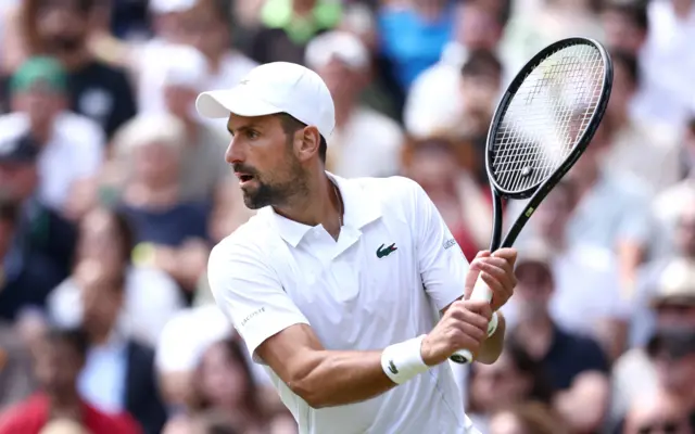 Novak Djokovic on court wearing all-white with a white cap