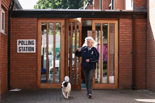 Suzanna Gray and her dog Leia, leave after she cast her vote in the 2024 General Election at Dundonald Elim Church in Belfast.