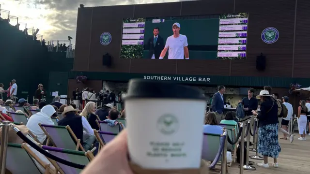 Tea cup and a large screen showing a tennis match