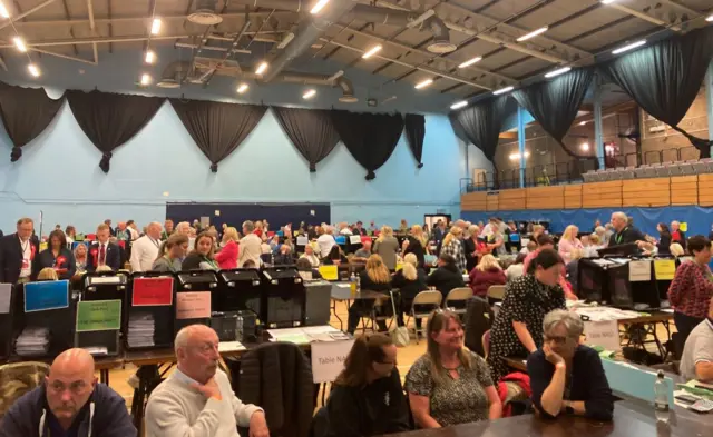 People sit at tables counting votes