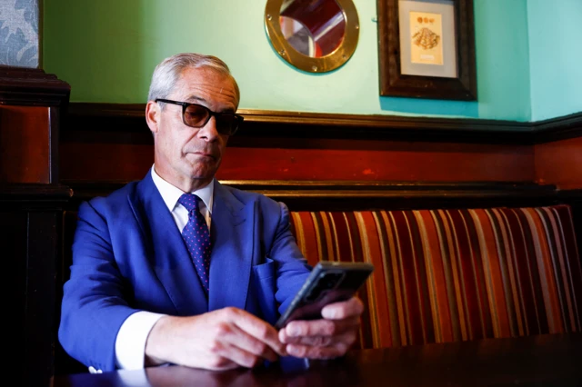 Nigel Farage pictured on his phone in a pub